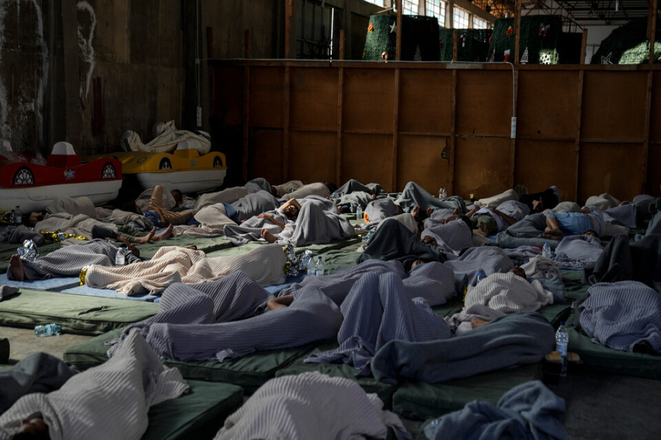 Överlevande sover på golvet i ett lager i staden Kalamatas hamn dagen efter att migrantbåten förliste.
