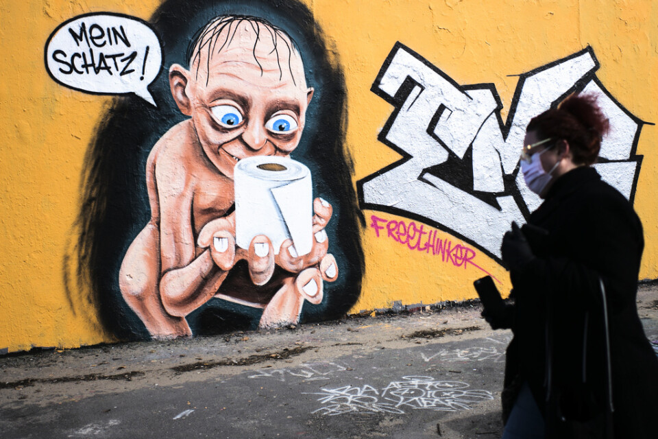 En kvinna går förbi en bild på "Sagan om ringen"-figuren Gollum, som har fått tag i en toalettpappersrulle och väser "min älskade". Väggen finns i Berlin. Arkivbild.