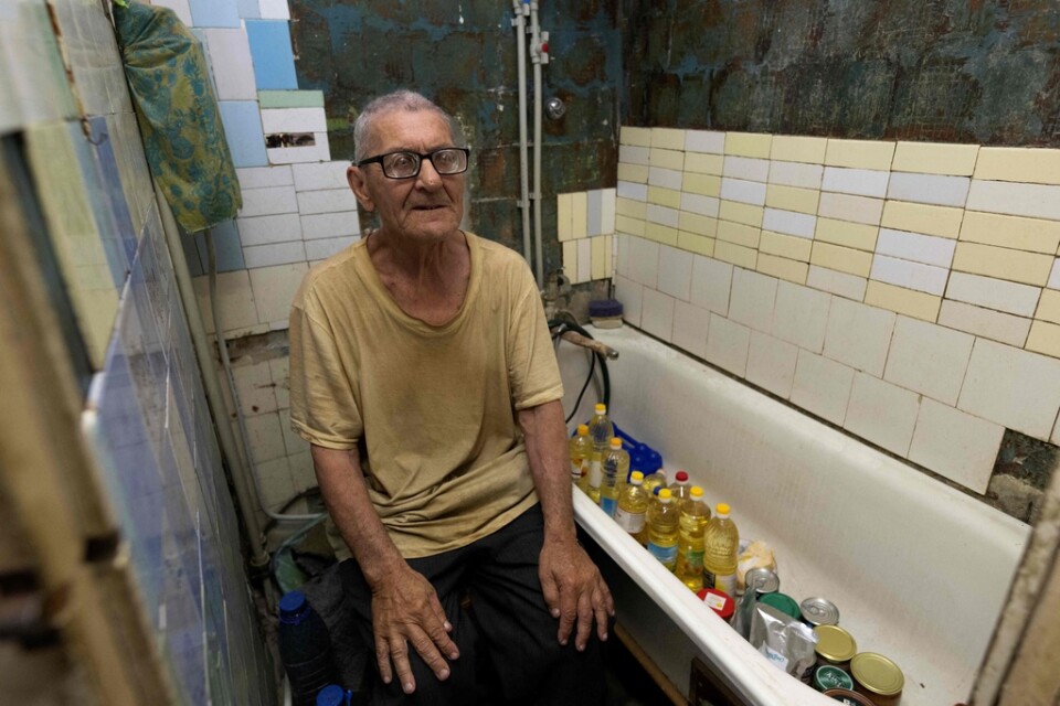 Viktor Grozdov förvarar bland annat solrosolja och konserver i sitt krigsskadade badrum i Avdijivka i östra Ukraina.