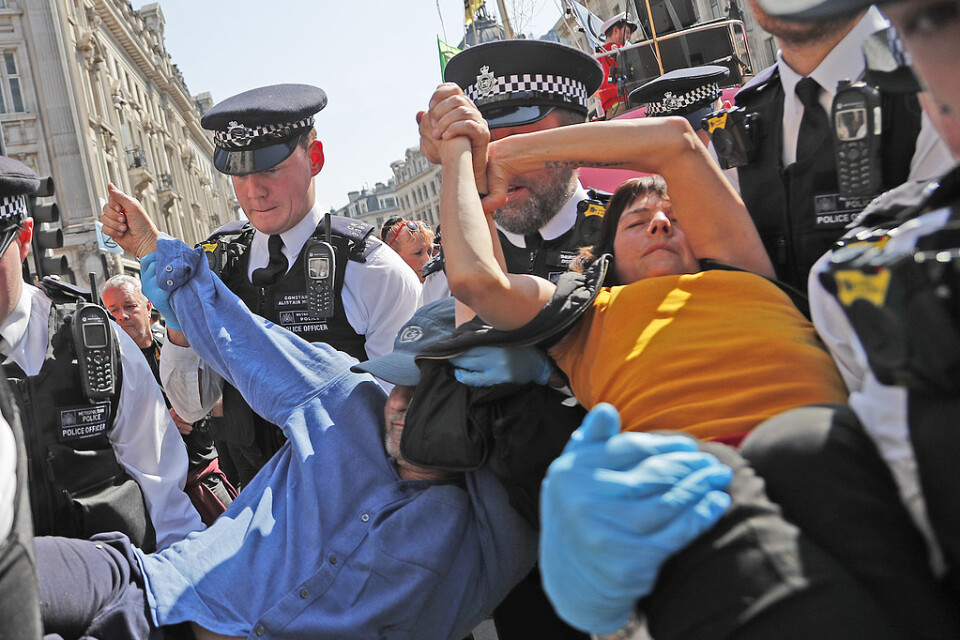 Poliser bär i väg ett par demonstranter som limmat ihop sina händer vid Oxford Circus i London på fredagen.