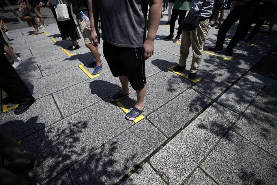 Besökare vid helgedomen Yasukuni Jinja köar med social distansering i ett försök att hindra smittspridning under årsdagen.