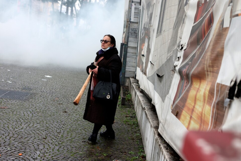 En kvinna, som känner sig hotad i sammandrabbningar i Tirana, tar till en trästock som försvar.