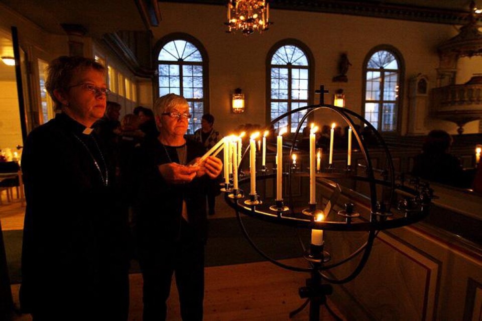 Katarina Redegard, diakon och Margareta Emanuelsson, ordförande i kyrkorådet tänder ljus i kyrkan.
