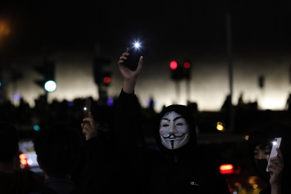 Demonstranter i Hongkong som bildat en mänsklig kedja håller upp sina telefoner med påslagna ficklampor under protester på nyårskvällen.
