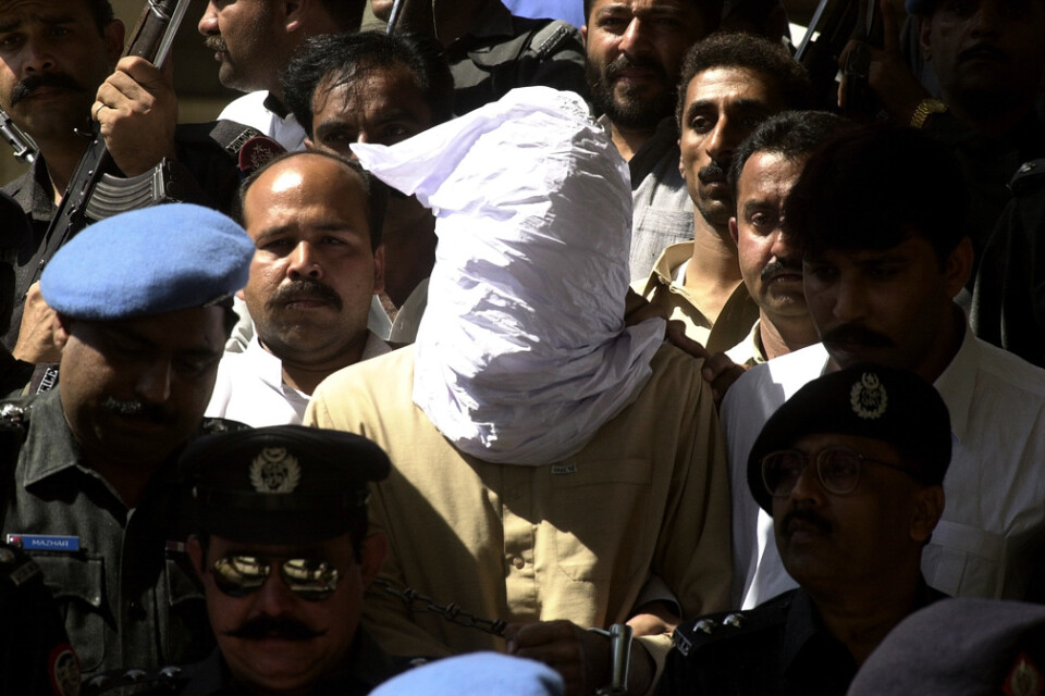 En person med täck ansikte, enligt polisens uppgifter Ahmed Omar Said som dömdes för mord på den amerikanske journalisten Daniel Pearl, förs in i rättegångssalen i Karachi i Pakistan 26 februari 2002.