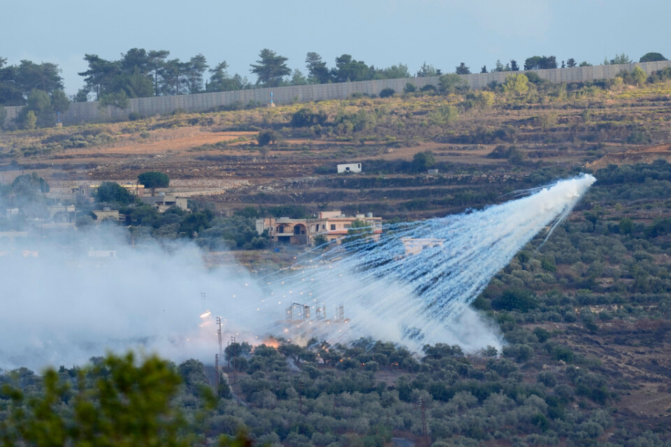 En israelisk artillerigranat exploderar över ett hus i al-Bustan, en libanesisk ort vid gränsen mot Israel, på söndagen.