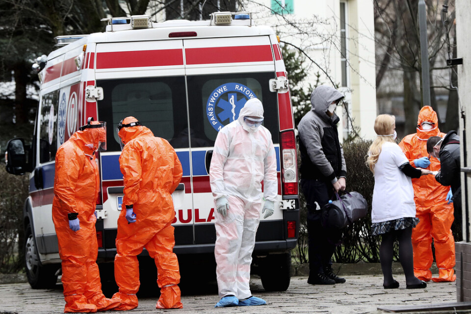 Ambulanspersonal i Warszawa transporterar en person som misstänks ha smittats av coronaviruset till sjukhus.