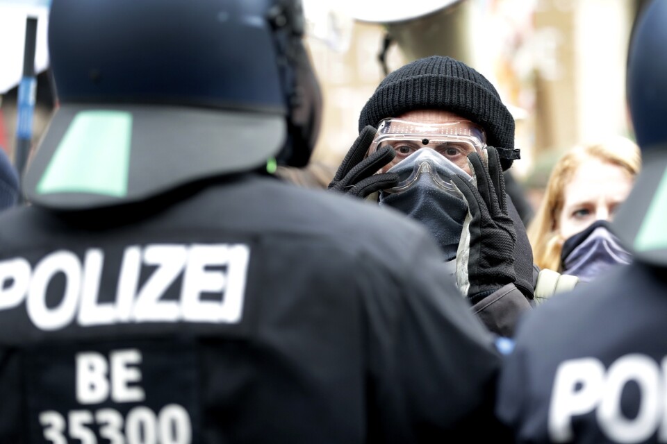Myndigheternas restriktioner väcker ilskna reaktioner i Tyskland. Här står en demonstrant framför poliser vid en demonstration i Berlin förra veckan. Arkivbild.