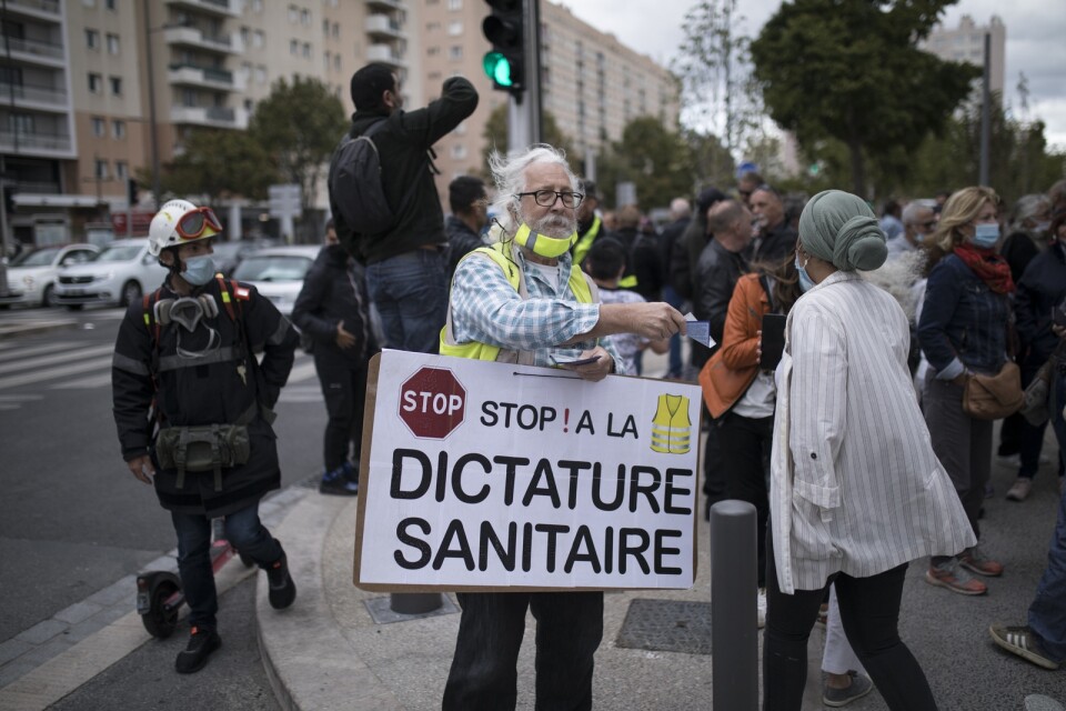 En man bär en skylt med texten "Stoppa hälsodiktaturen" utanför sjukhuset i Marseille som besöktes av Frankrikes hälsominister under fredagen.