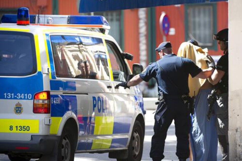 Polisen för bort den misstänkte rånaren med en handduk över huvudet sedan han ska ha hotat personalen och en kund på ett bankkontor vid Östermalmstorg i Stockholm på fredagseftermiddagen.