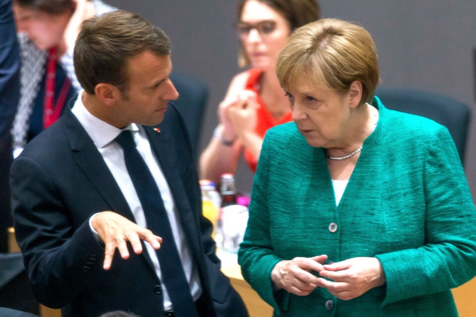 German Chancellor Angela Merkel, right, speaks with French President Emmanuel Macron during a round table meeting at an EU summit in Brussels, Thursday, June 28, 2018. European Union leaders meet for a two-day summit to address the political crisis over migration and discuss how to proceed on the Brexit negotiations. (Stephanie Lecocq, Pool Photo via AP)