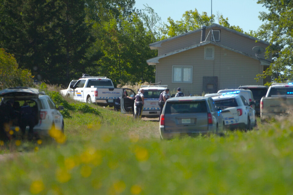 Polisen har omringat en bostad i letandet efter en av de bröder som misstänks för att i söndags ha mördat tio personer i Kanada.