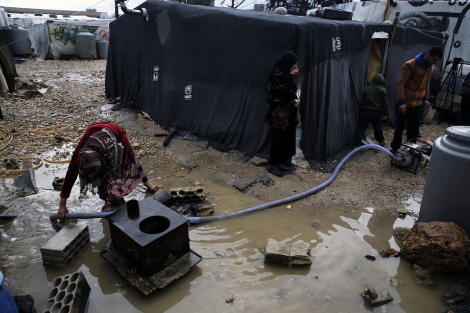 En flyktingfamilj pumpar bort vatten i ett flyktingläger i Bekaadalen i Libanon efter kraftiga regn i januari i fjol. Arkivbild.