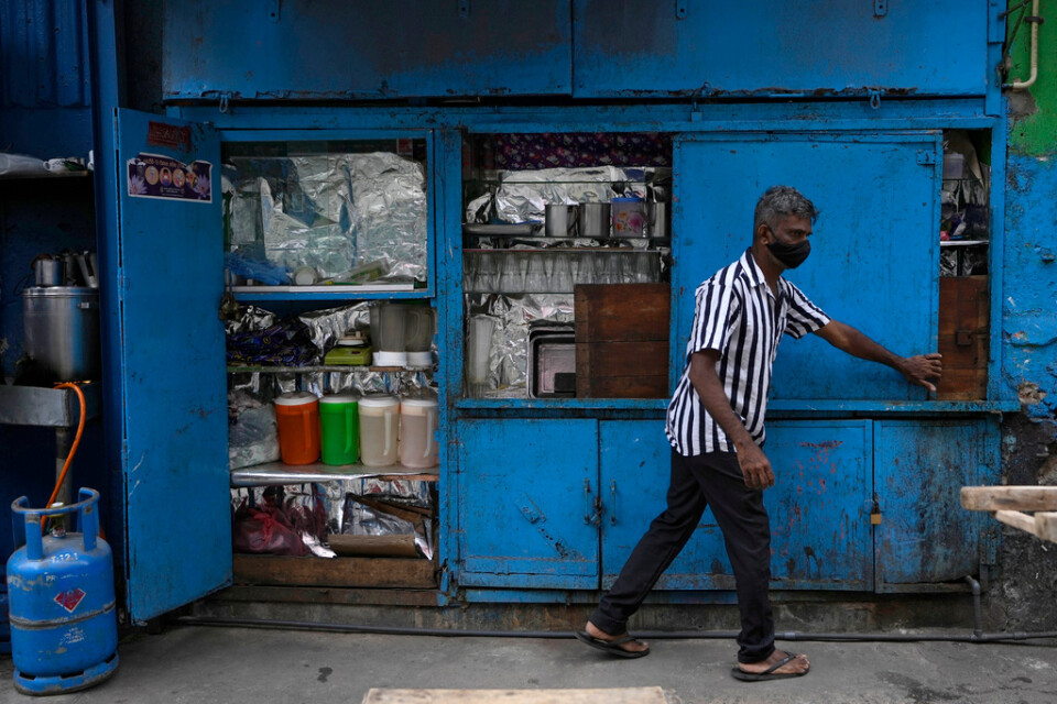En man öppnar sitt gatukök i Colombo en morgon i oktober. Genrebild.
