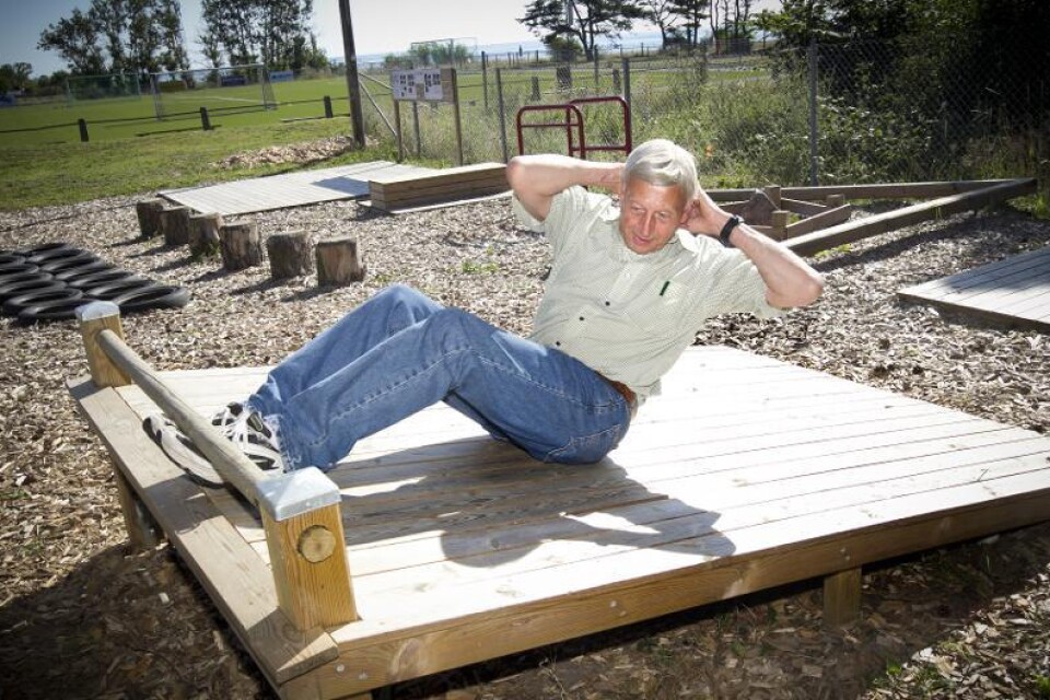 Karl Bertil Lindberg, 73 år, visar hur man kan köra sit-ups på det nya utegymmet som ligger i direkt anslutning till byns idrottsplats. Den som vill jogga i samband med styrketräningen på gymmet har tre olika slingor att välja mellan.