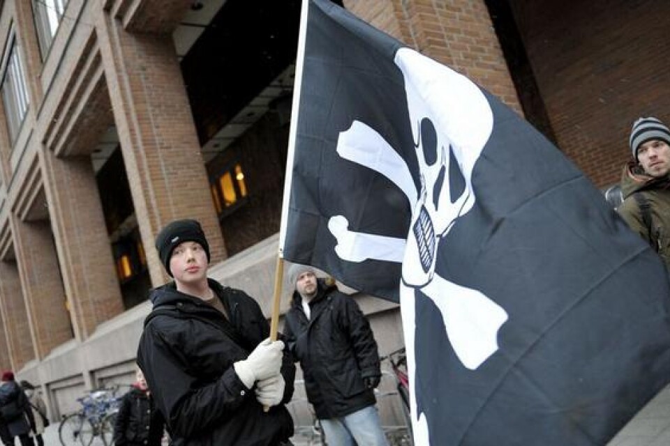 Rättegången mot männen bakom The Pirate Bay inleddes på måndagen i Stockholms tingsrätt. En knapp halvtimme innan dörrarna i rättssalen slogs upp demonstrerade ett 20-tal personer utanför tingsrättens lokaler på Kungsholmen i centrala Stockholm. De viftade med svarta piratflaggor till stöd för de åtalade. På tisdagen fortsatte rättegången. Bild: Scanpix