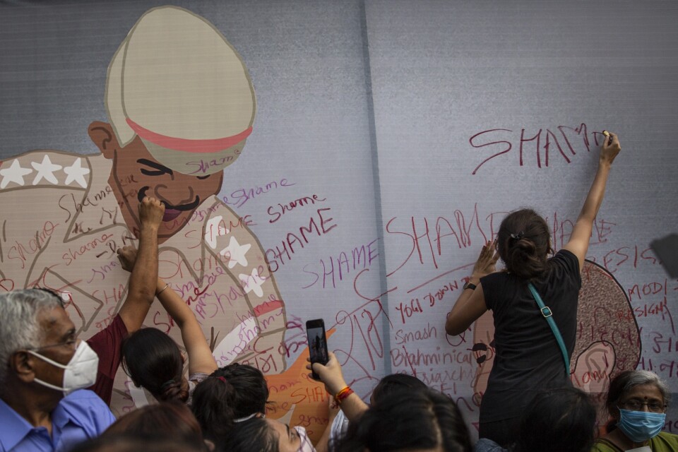 Aktivister klottrar på en karikatyr av en polis under en protest mot sexuellt våld i Indien i fredags.