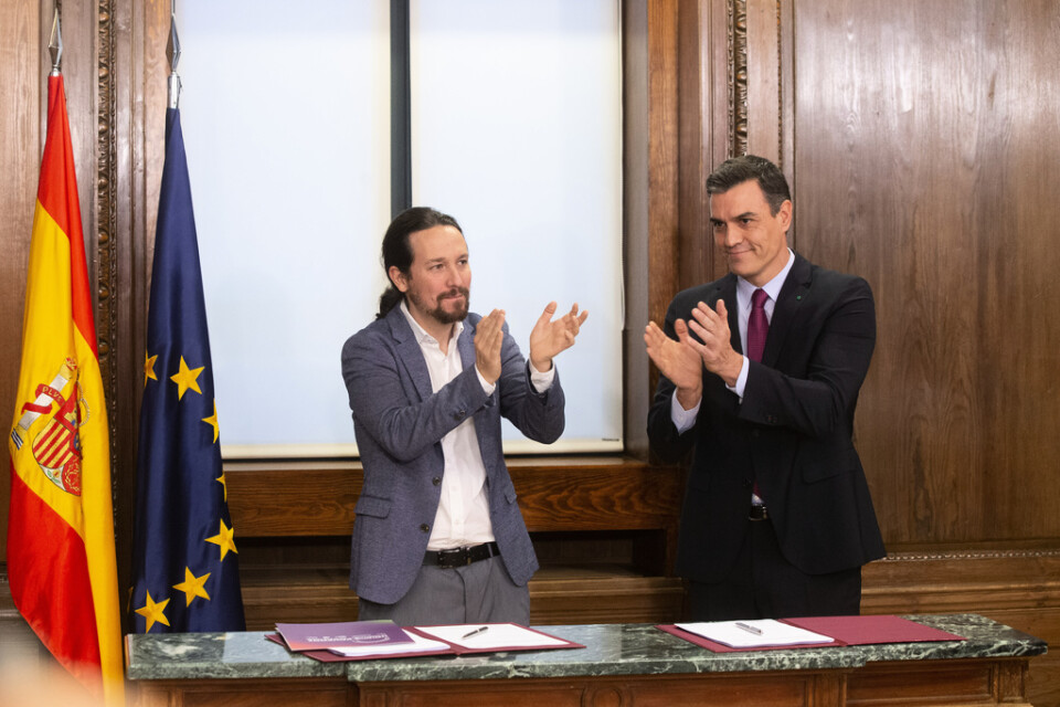Unidas Podemos ledare Pablo Iglesias och PSOE-ledaren Pedro Sánchez applåderar de som förhandlat å deras respektive partiers vägnar, i samband med att de signerar regeringsunderlaget i Madrid på måndagen.