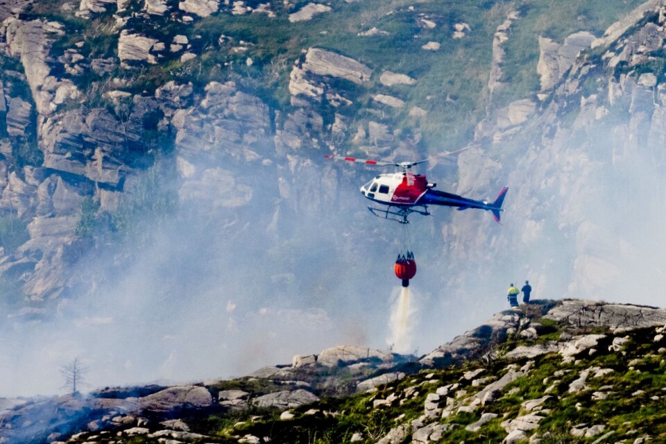 Räddningstjänsten jobbar hårt för att släcka gräsbranden på den norska ön Sotra.