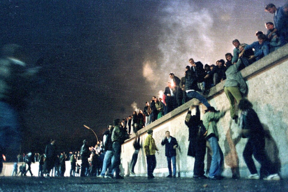 En sliten, lite oskarp bild av krafterna bakom längtan efter frihet. Östberlinare klättrar över muren vid Brandenburger Tor natten mellan 9 och 10 November 1989.