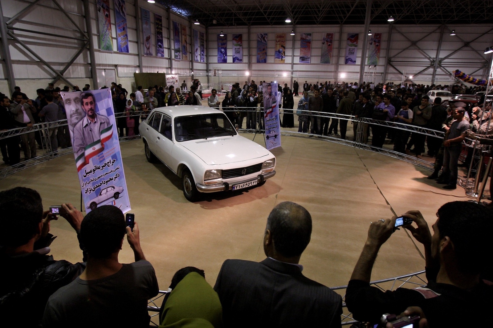 Iranians take photographs of Iranian President Mahmoud Ahmadinejad's car, as it is displayed at an auto show for auction for a charity in the city of Abadan, 600 miles (1000 kilometers) southwest of the capital Tehran, Iran, Wednesday, Feb. 23, 2011. Iran's populist president is putting his 33-year-old Peugeot up for auction for a charity that funds housing projects for young people. Ahmadinejad's move is seen as a bid to appeal to the young and attract attention to housing projects he espoused during his campaigns, promising to put a roof over the head of every poor Iranian. (AP Photo/Vahid Salemi) / SCANPIX Code: 436