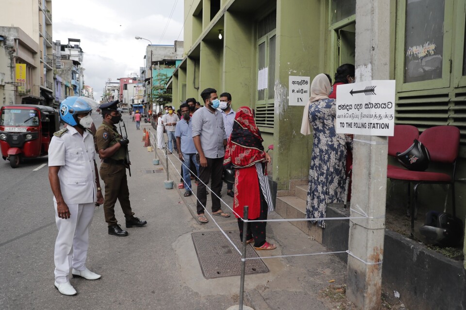 Hälsoinspektörer kontrollerade att människor höll sig till virusrestriktionerna. Här i en kö in till en vallokal i Colombo.