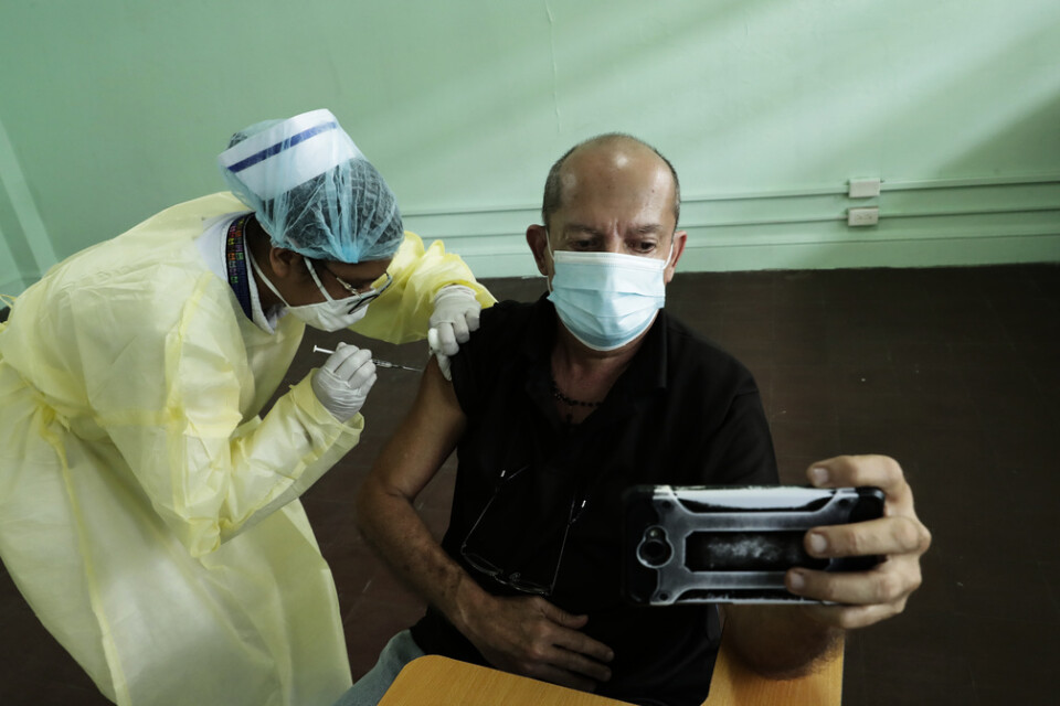 En man i Panama City tar en bild när han får en vaccinspruta. Arkivbild.