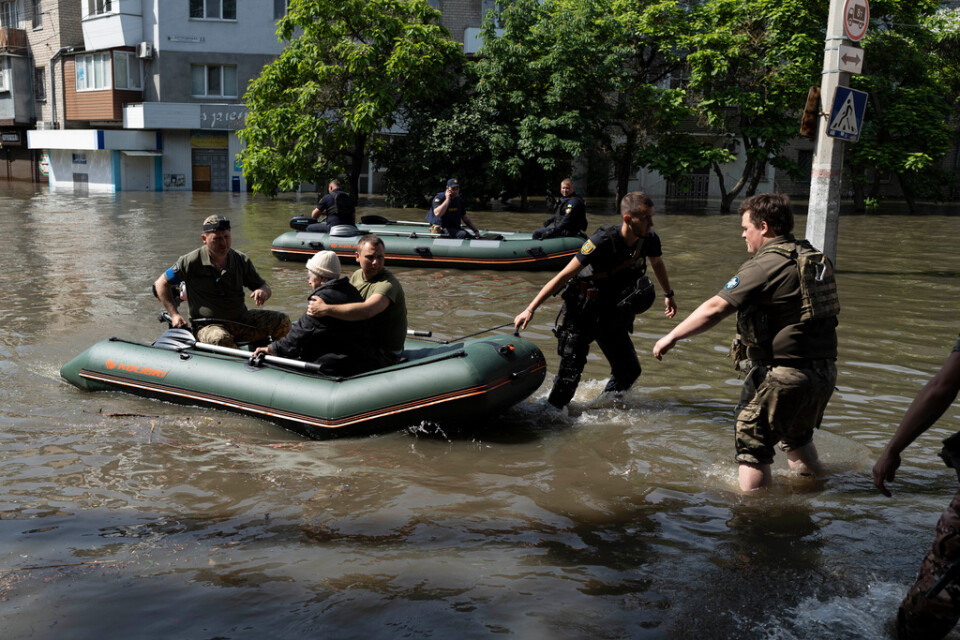 En kvinna evakueras i en gummibåt sedan flodvattnet vällt in.