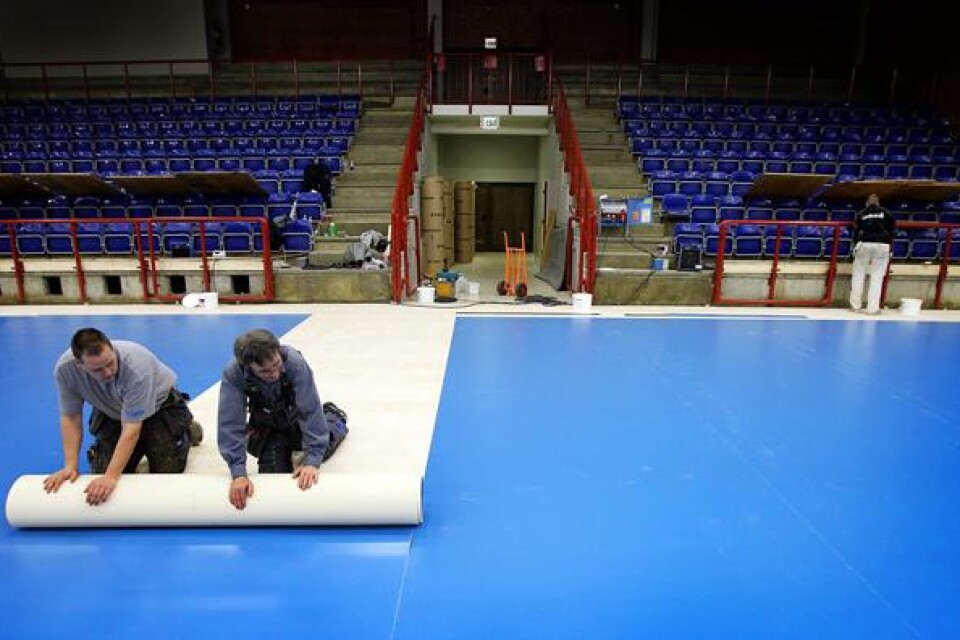Mikael Påhlsson och Arne Jeppsson lägger handbollsgolv. Totalt ska cirka 25 våder rullas ut på den 950 kvadratmeter stora ytan.