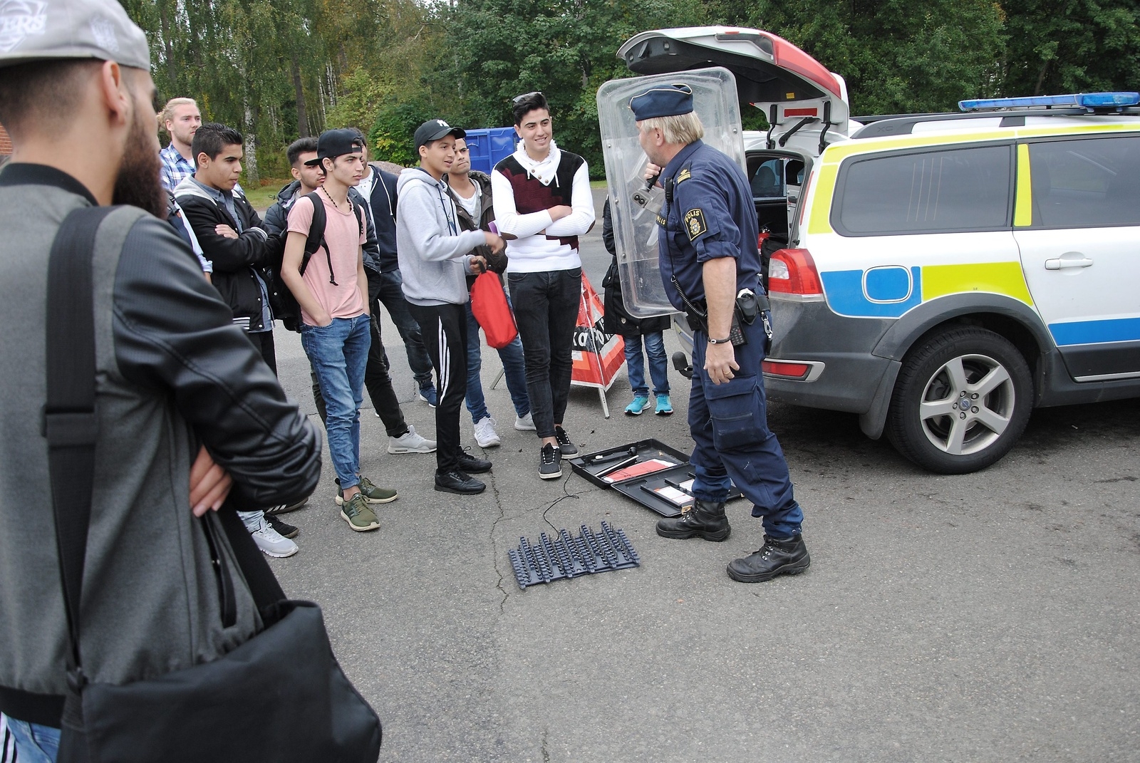 Rolf Paimensalo, kommunpolis, visar upp polisens utrustning för nyanlända elever.