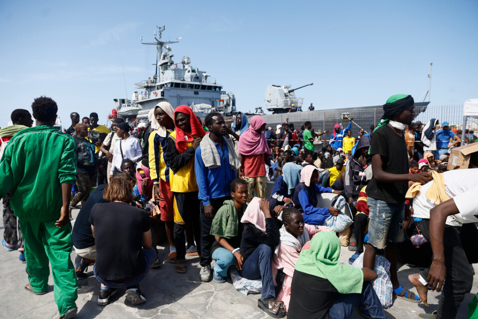 Migranter utanför Röda Korsets mottagningscenter på den italienska ön Lampedusa, en så kallad "hot spot" där ingen är tänkt att stanna mer än tre dygn.