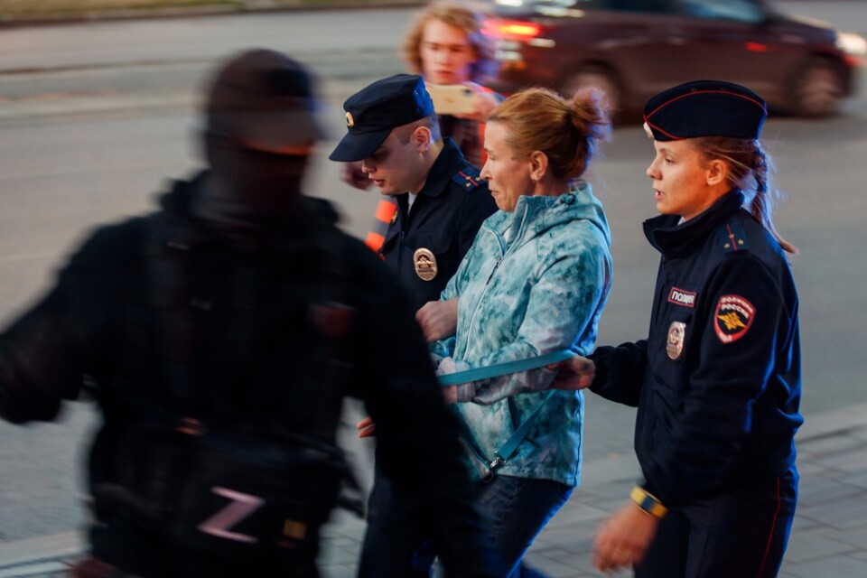 En kvinna leds iväg av poliser vid protester i Jekaterinburg. Den maskerade polisen i förgrunden bär ett "Z", som kommit att bli en rysk symbol till stöd för krigsinsatsen i Ukraina.