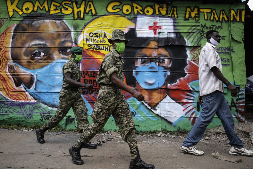 Folk passerar förbi en väggmålning med coronamotiv i slumområdet Mathare utanför huvudstaden Nairobi i Kenya. Arkivbild.