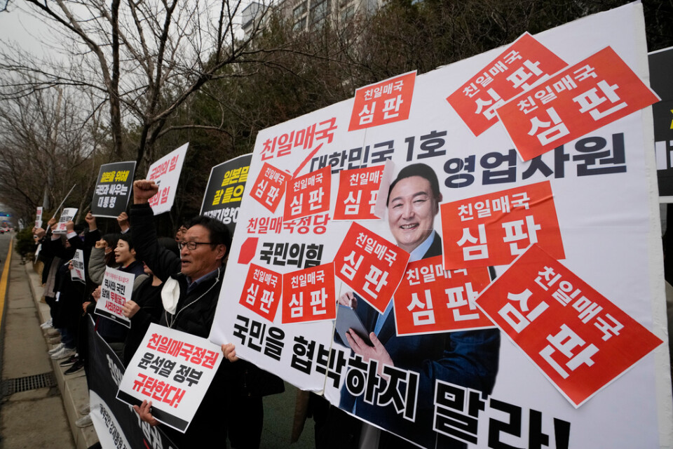 Sydkoreas president Yoon Suk-Yeol ska till Japan. Här syns han på ett plakat vid en av veckans protestaktioner mot honom.