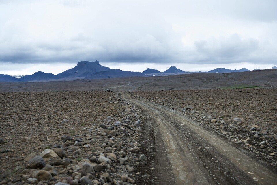 En grusväg i ett öppet stenlandskap på Island.