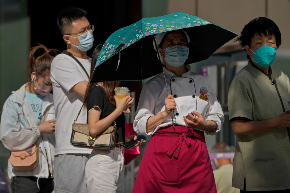 Pekingbor i munskydd väntar på att få sina rutinmässiga covidtest tagna vid ett testcenter i den kinesiska huvudstaden.