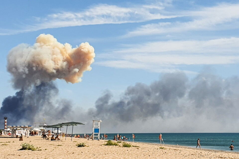 Rökmoln syns från en strand i närheten efter explosionerna vid en rysk militärbas på den ockuperade Krimhalvön.