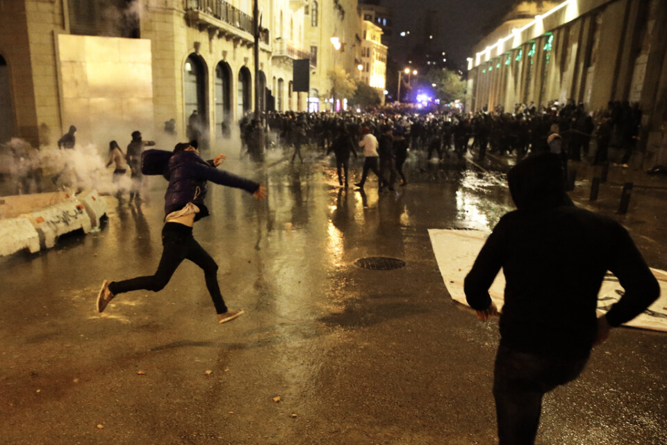 Demonstranter kastar stenar mot kravallpolis under de pågående protesterna i Beirut.