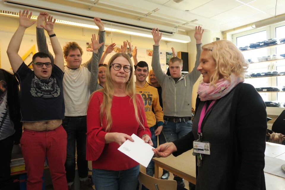 Elever och lärare jublar i bakgrunden när Maria Brännström från Rebeckalogen delar ut en penninggåva till Lise-Lotte Håkansson, lärare vid särskolan på Oscarsgymnasiet.