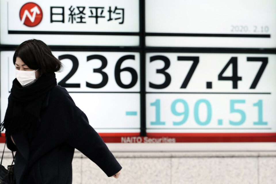 En kvinna passerar en elektronisk tavla som visar Japans Nikkei|225-index.