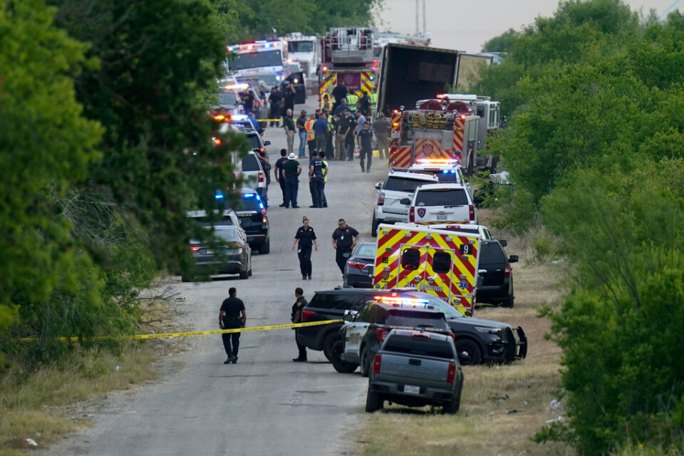 Polis, ambulans och räddningstjänst arbetar vid platsen där många migranter hittades döda i en lastbil i södra Texas i måndags.