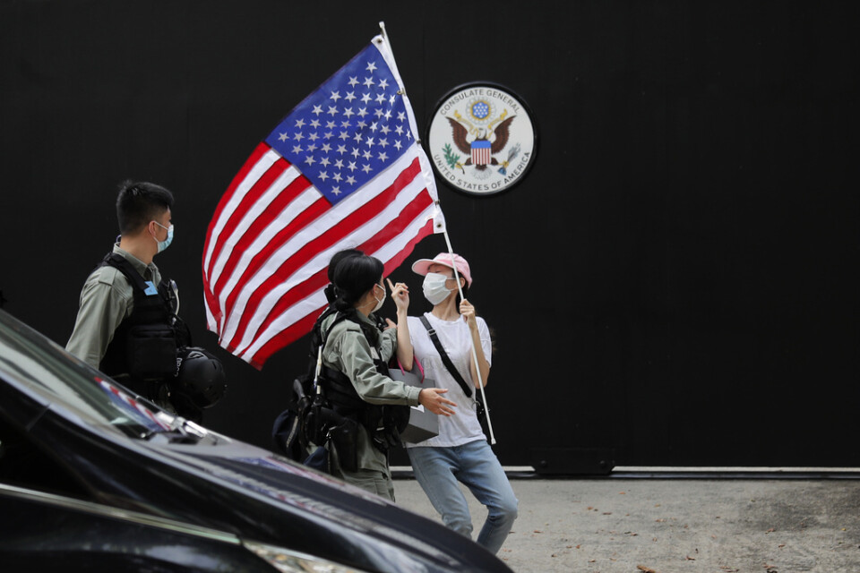 En aktivist med en amerikansk flagga motas bort av polis vid en manifestation utanför USA:s konsultat i Hongkong den 4 juli.