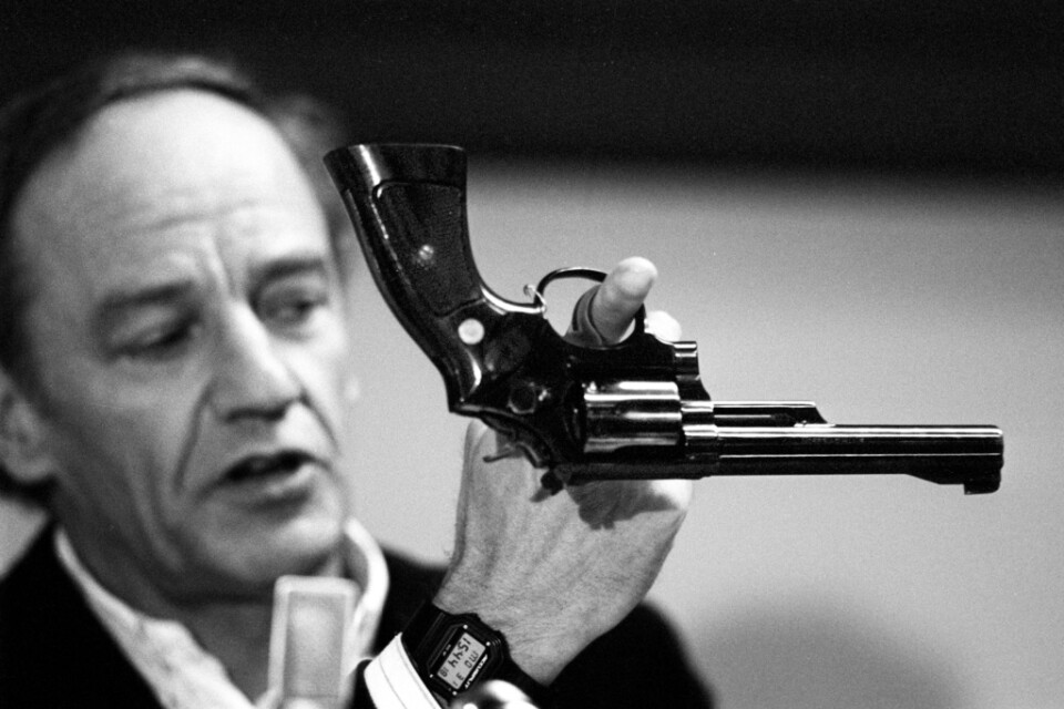 Länspolismästaren och spaningsledaren Hans Holmér håller upp en revolver vid en presskonferens i mars 1986. Arkivbild.