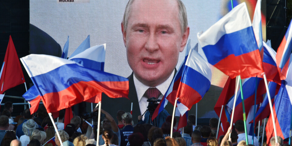 Människor ser på storbilds-tv president Vladimir Putin hålla tal inför annekteringen av fyra områden i Ukraina.
