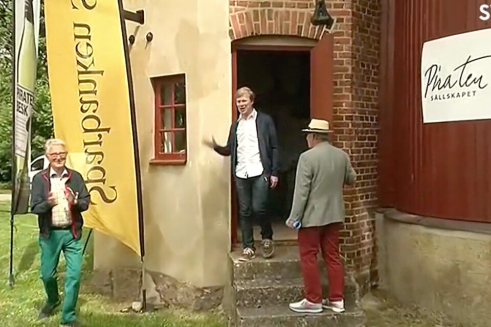 Komikern Johan Glans vinkar till församlingen utanför Pumphuset i Vollsjö.