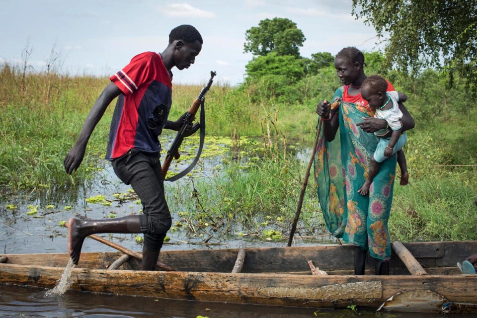 En rebellsoldat och en mamma med barn bordar en kanot för att försöka ta sig till ett flyktingläger.