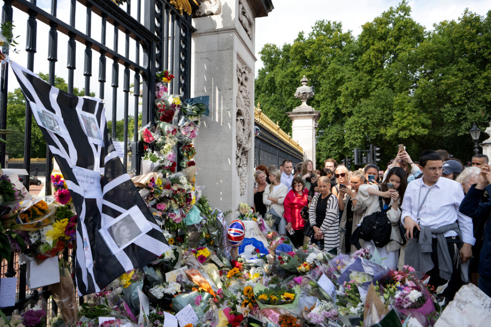 Människor lägger blommor utanför Buckingham Palace i London med anledning av drottning Elizabeth bortgång.