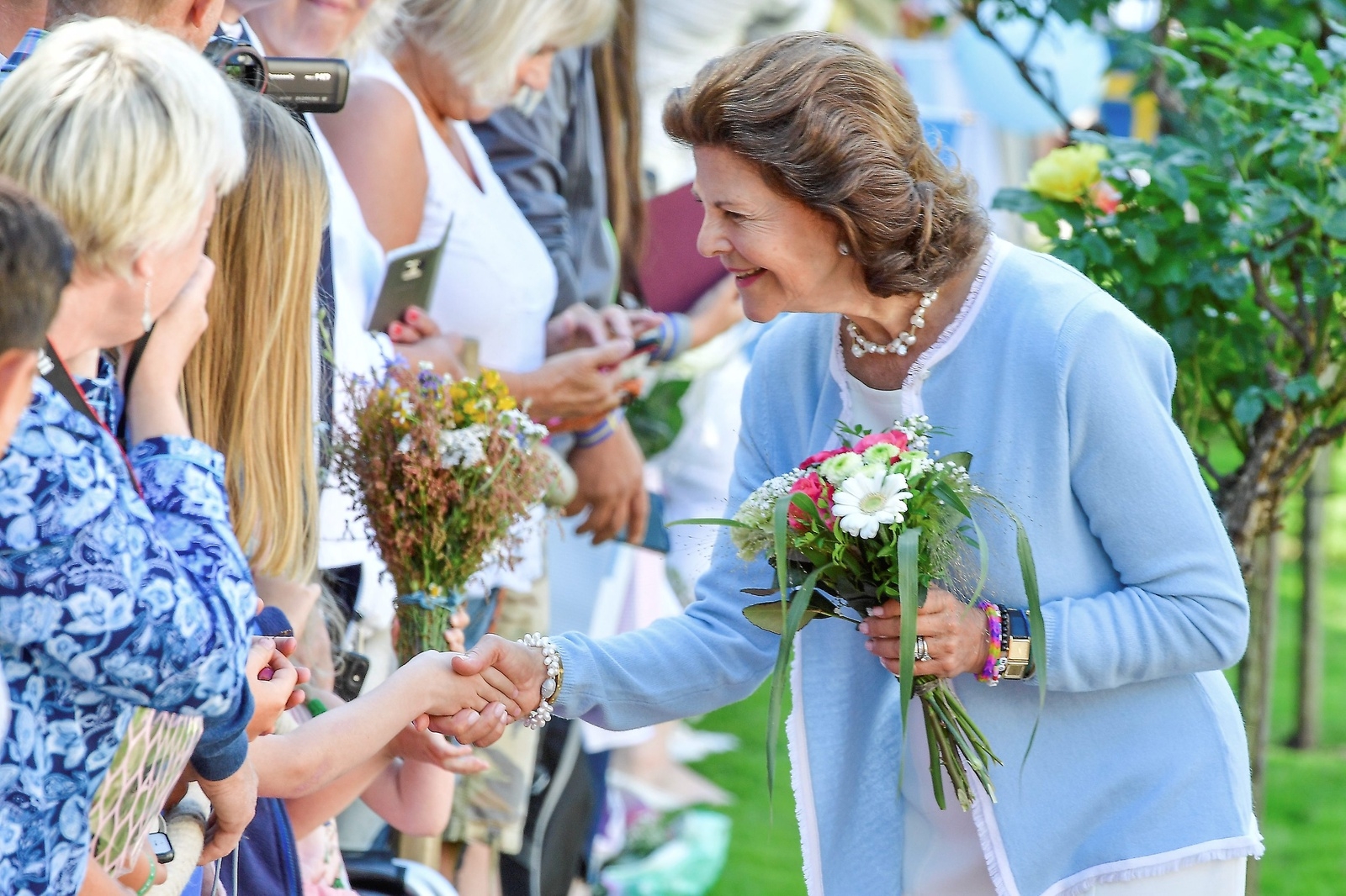 Drottning Silvia får blommor av de som samlats på Solliden för att fira kronprinsessan Victorias 40-årsdag. 
Foto: Mikael Fritzon/TT