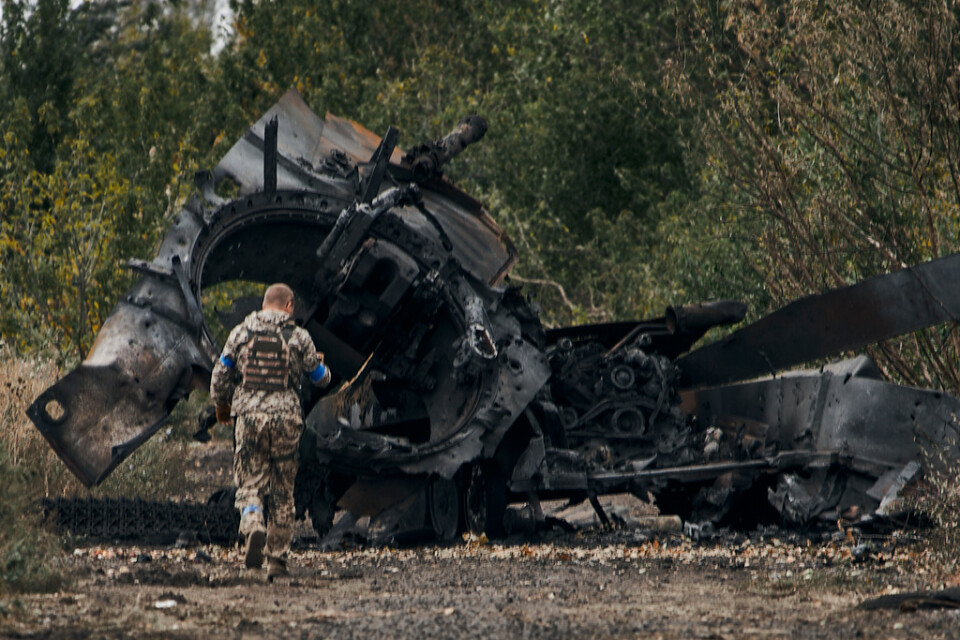 Ukrainsk soldat vid en förstörd rysk stridsvagn i nyligen återerövrade territorier i Charkivregionen.