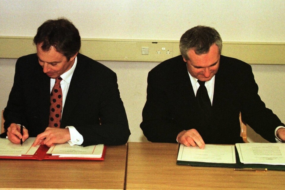 Storbritanniens premiärminister Tony Blair (vänster i bild) skriver under Långfredagsavtalet sida vid sida med Irlands premiärminister Bertie Ahern, i Belfast den 10 april 1998.